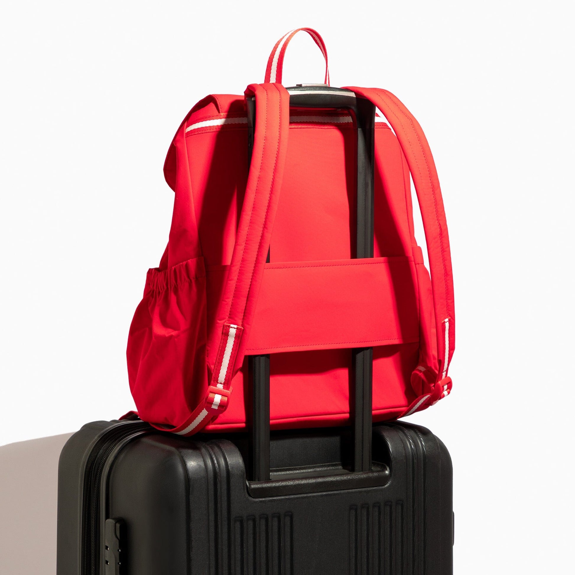 Cherry Motion Drawcord Backpack in red, attached to luggage.