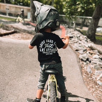 Child on bike wearing black APEX LIVE FAST TEE with helmet.