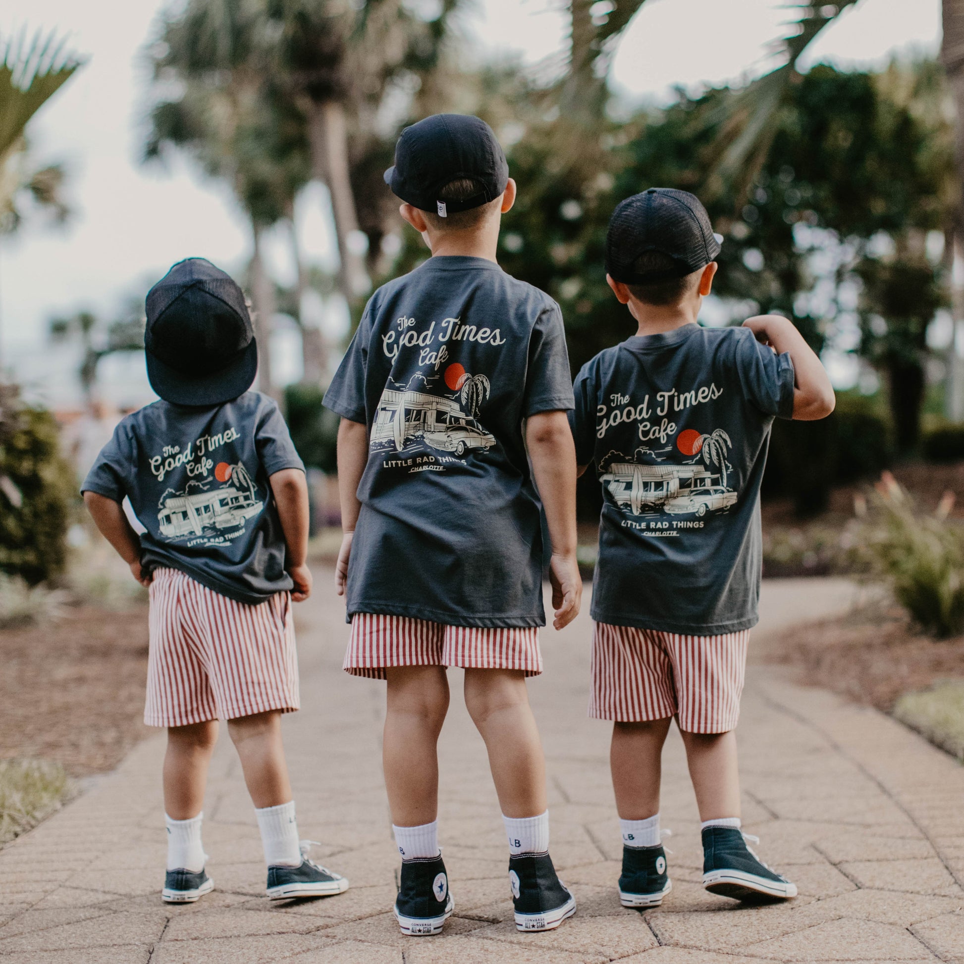 Three boys wearing The Good Times Cafe Tee with matching shorts and hats.