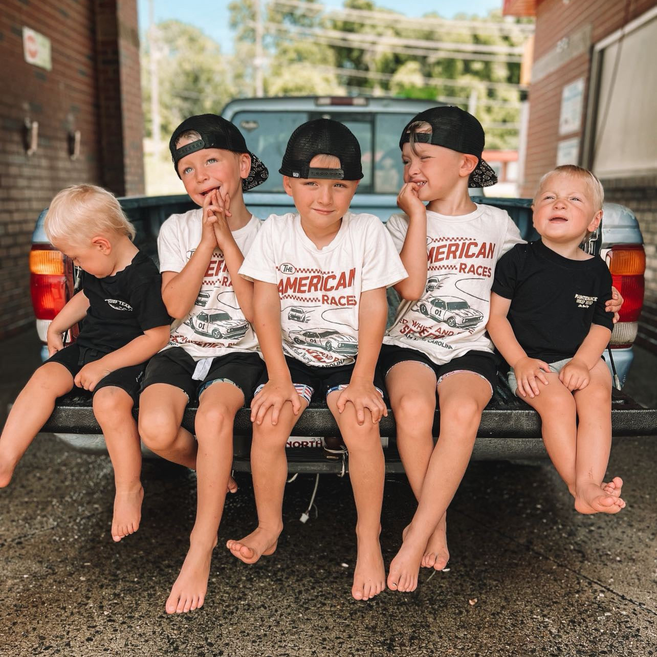 Group of kids wearing The All American Races cream tee shirt.