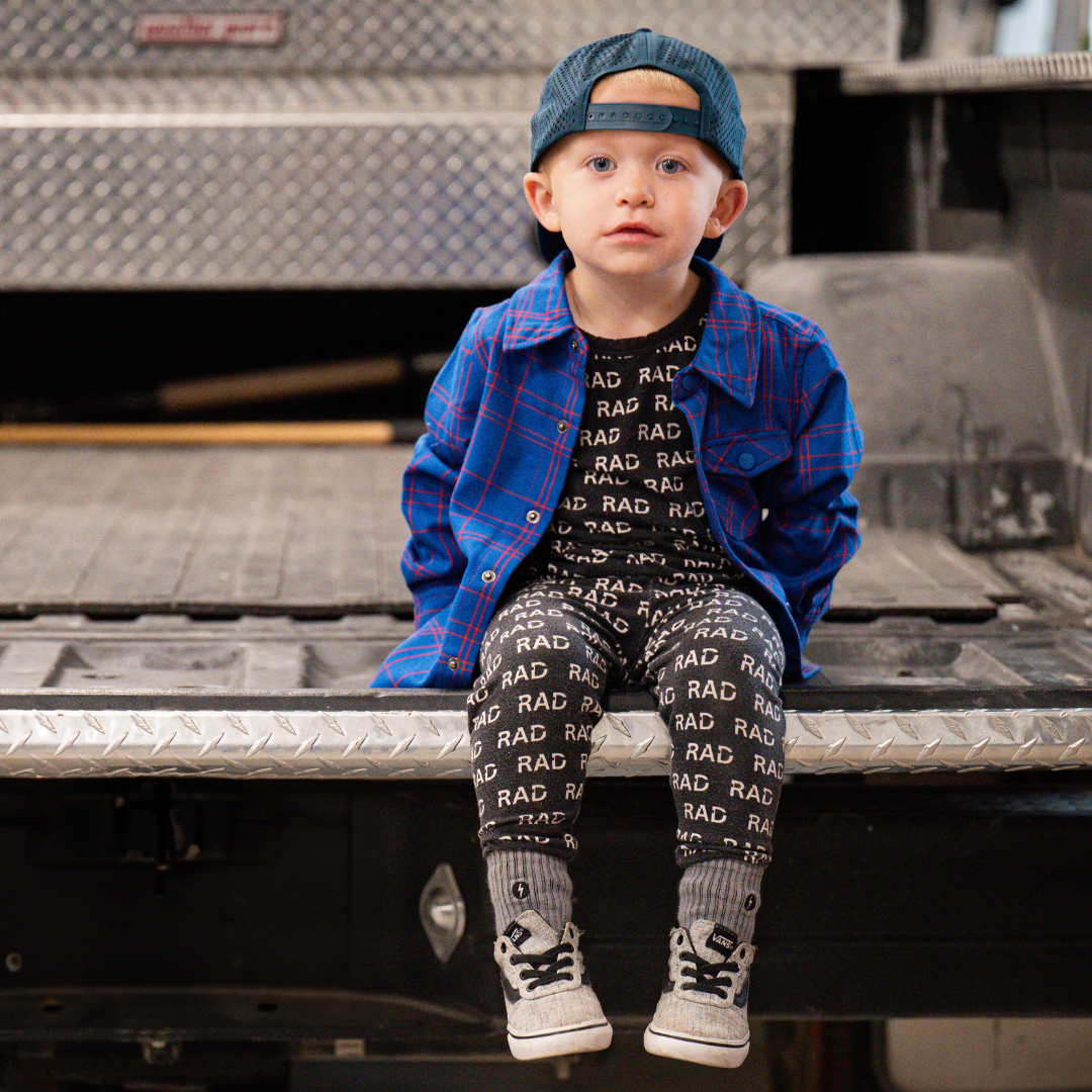 Boy in blue and red plaid Kids Fast and Free Flannel with jeans and red sneakers