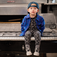 Boy in blue and red plaid Kids Fast and Free Flannel with jeans and red sneakers