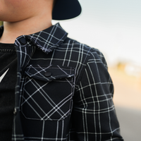 Close-up of black and white plaid Kids Flip Side Flannel with functional pockets.