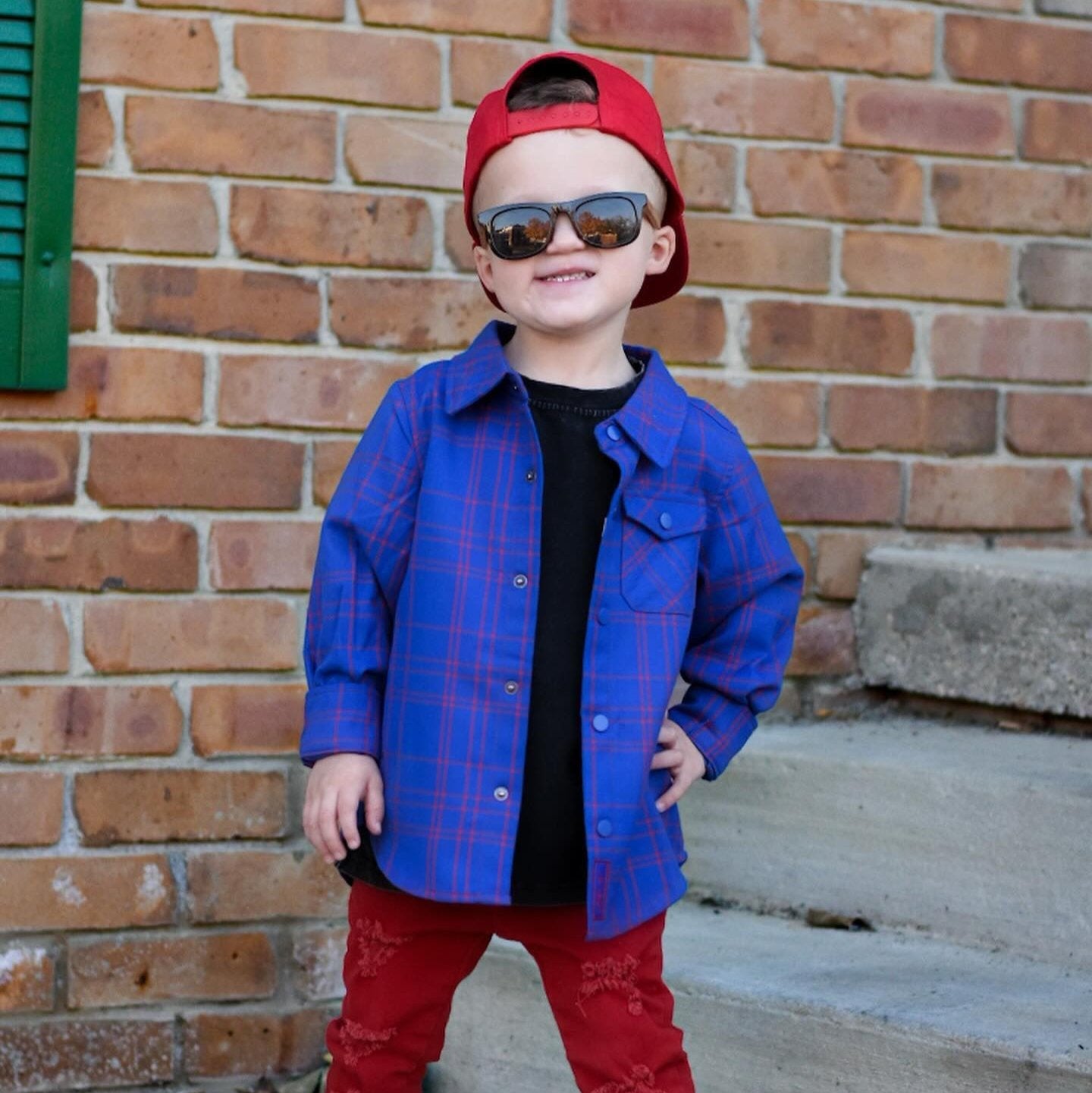 Boy in blue and red plaid Kids Fast and Free Flannel with jeans and red sneakers
