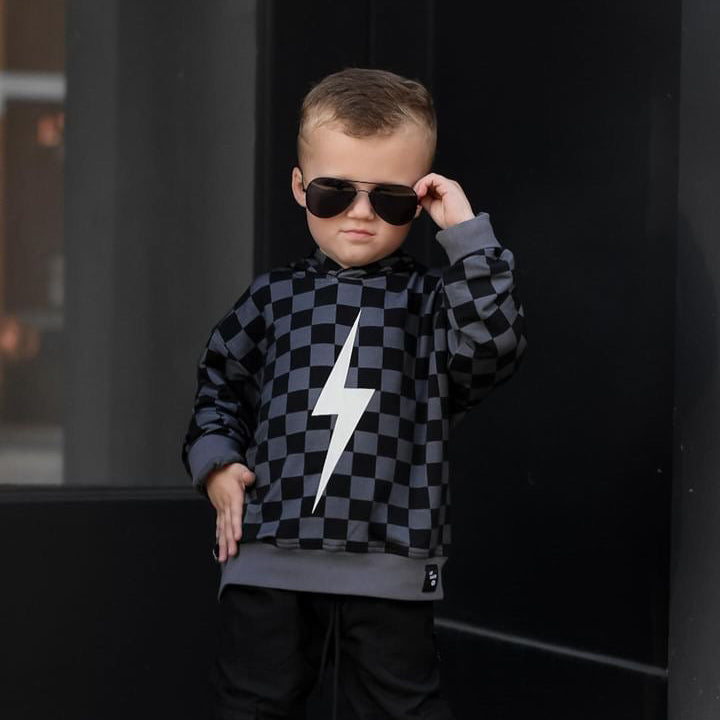 Boy in black checkered Spark Hoodie adjusts sunglasses.