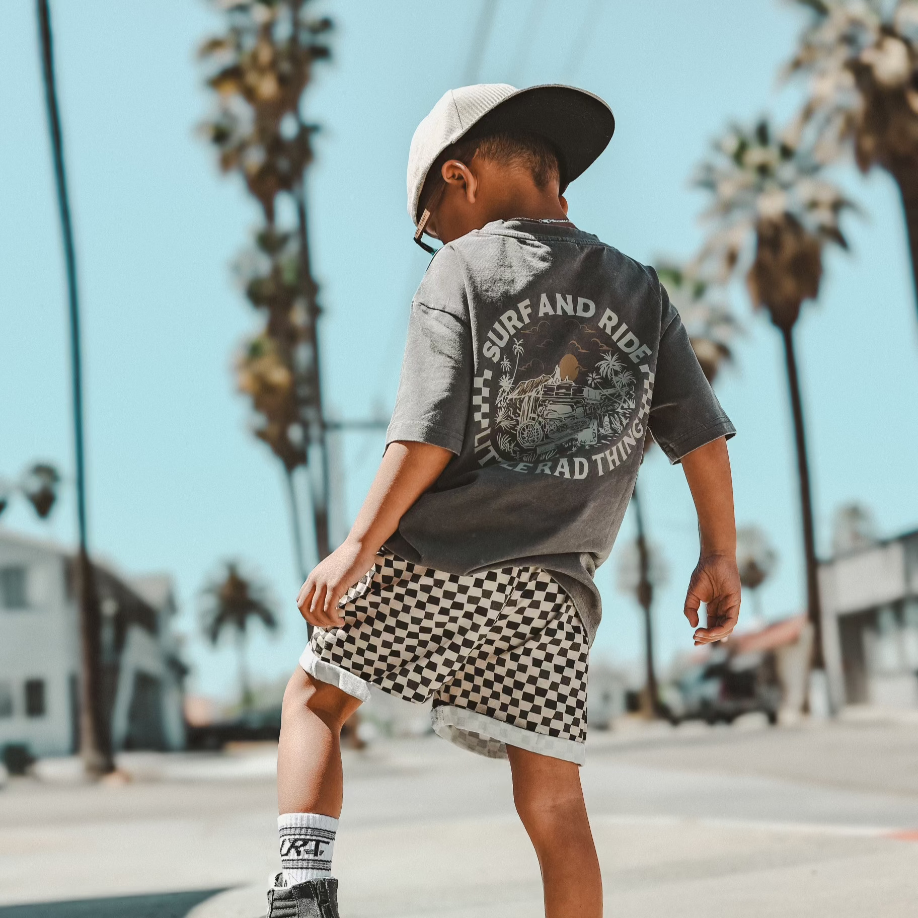Boy wearing Surf N Ride tee with checkerboard shorts
