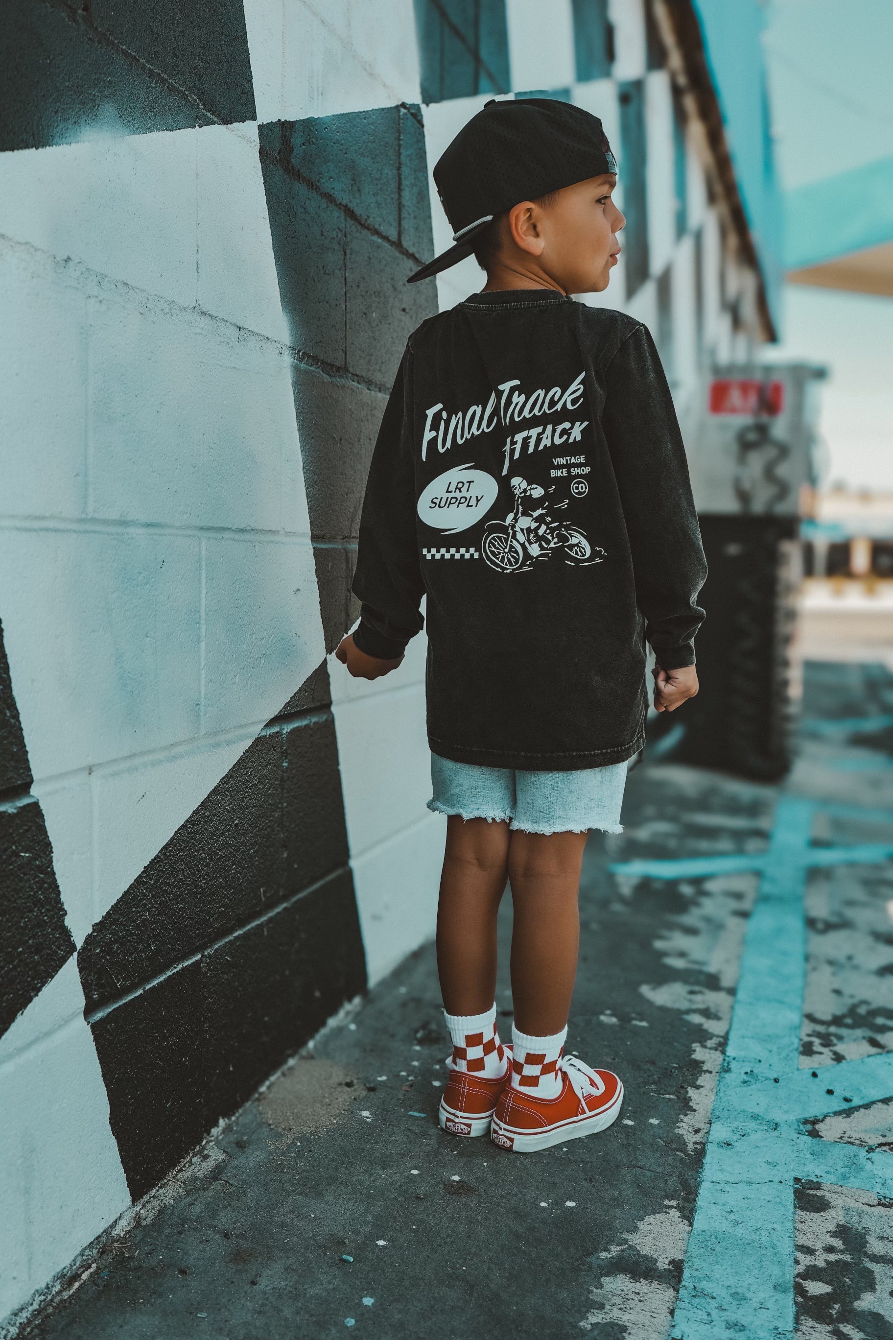 Boy in Final Track Attack long sleeve tee, shorts, and red sneakers