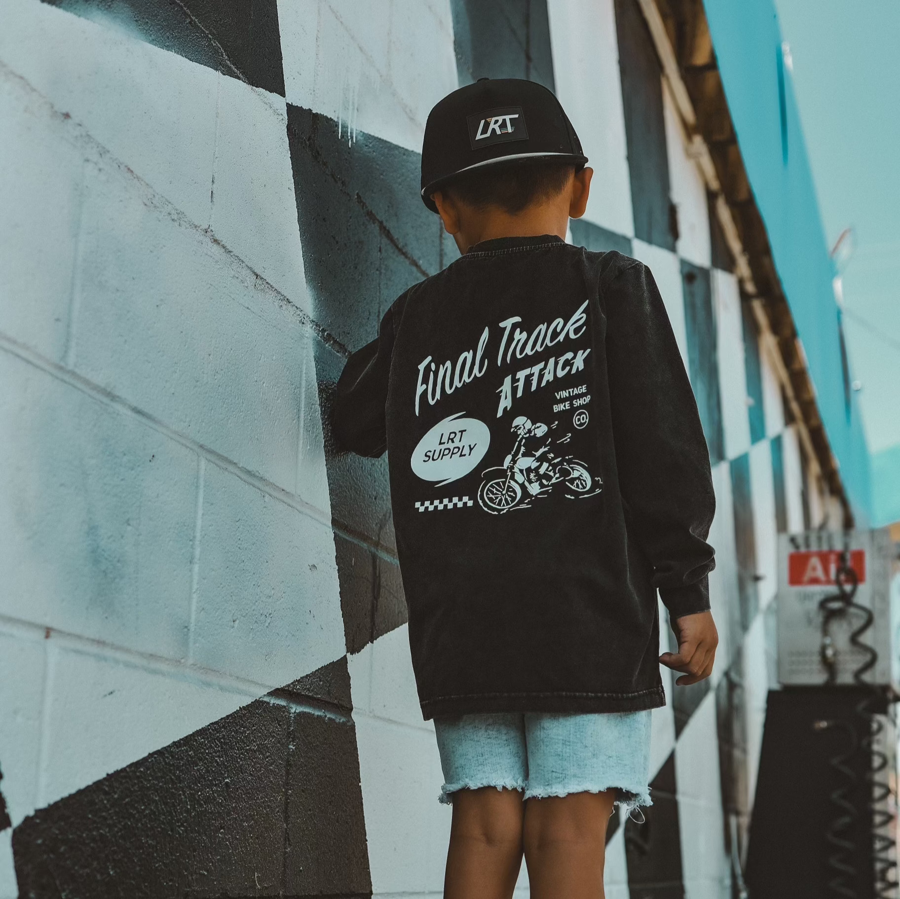 Child in Ocean Cubs Wear black Final Track Attack shirt near mural