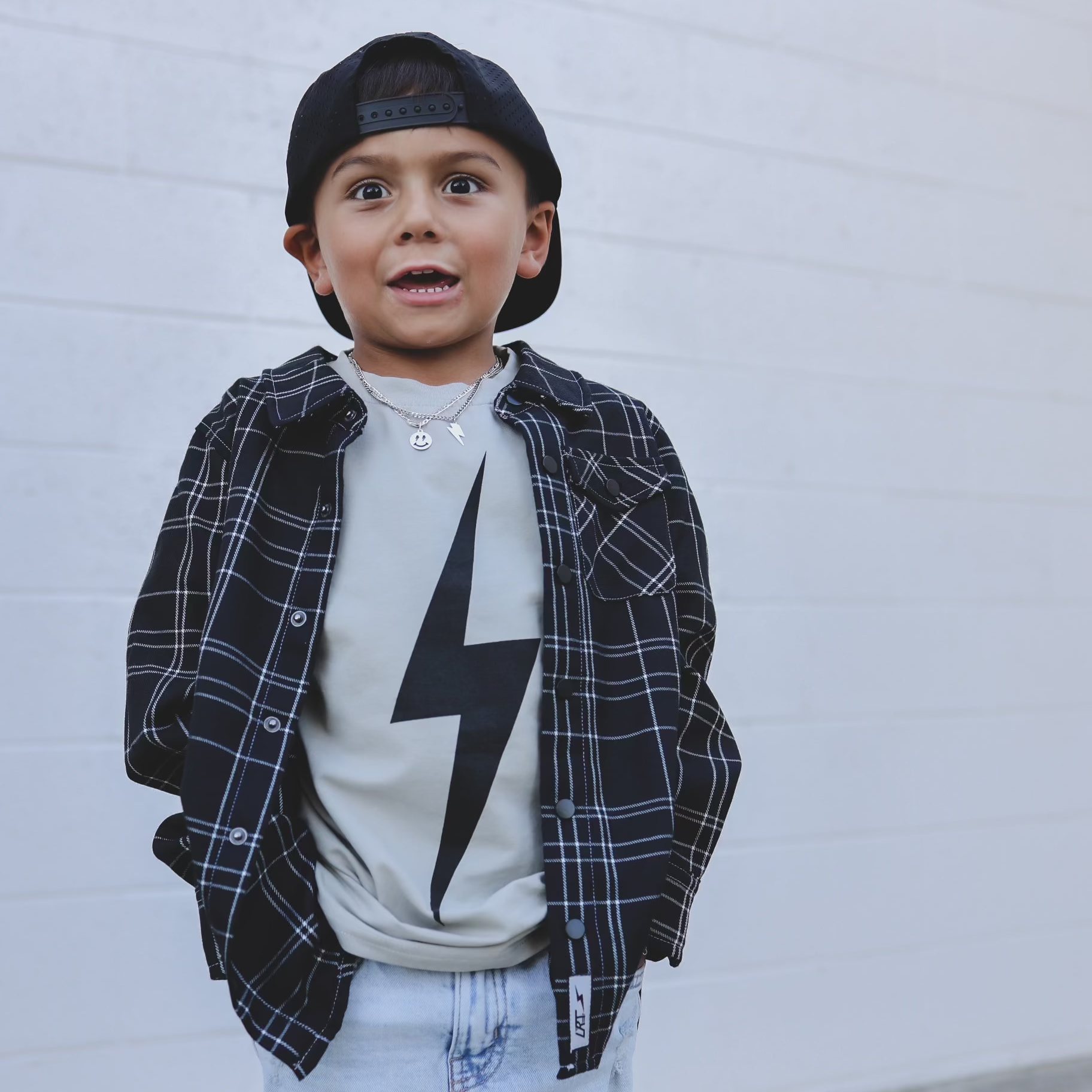 Boy wearing Greige Acid Wash Spark Tee with a black plaid shirt
