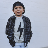 Boy wearing Greige Acid Wash Spark Tee with a black plaid shirt