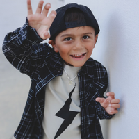 Smiling boy in Greige Acid Wash Spark Tee and black plaid shirt