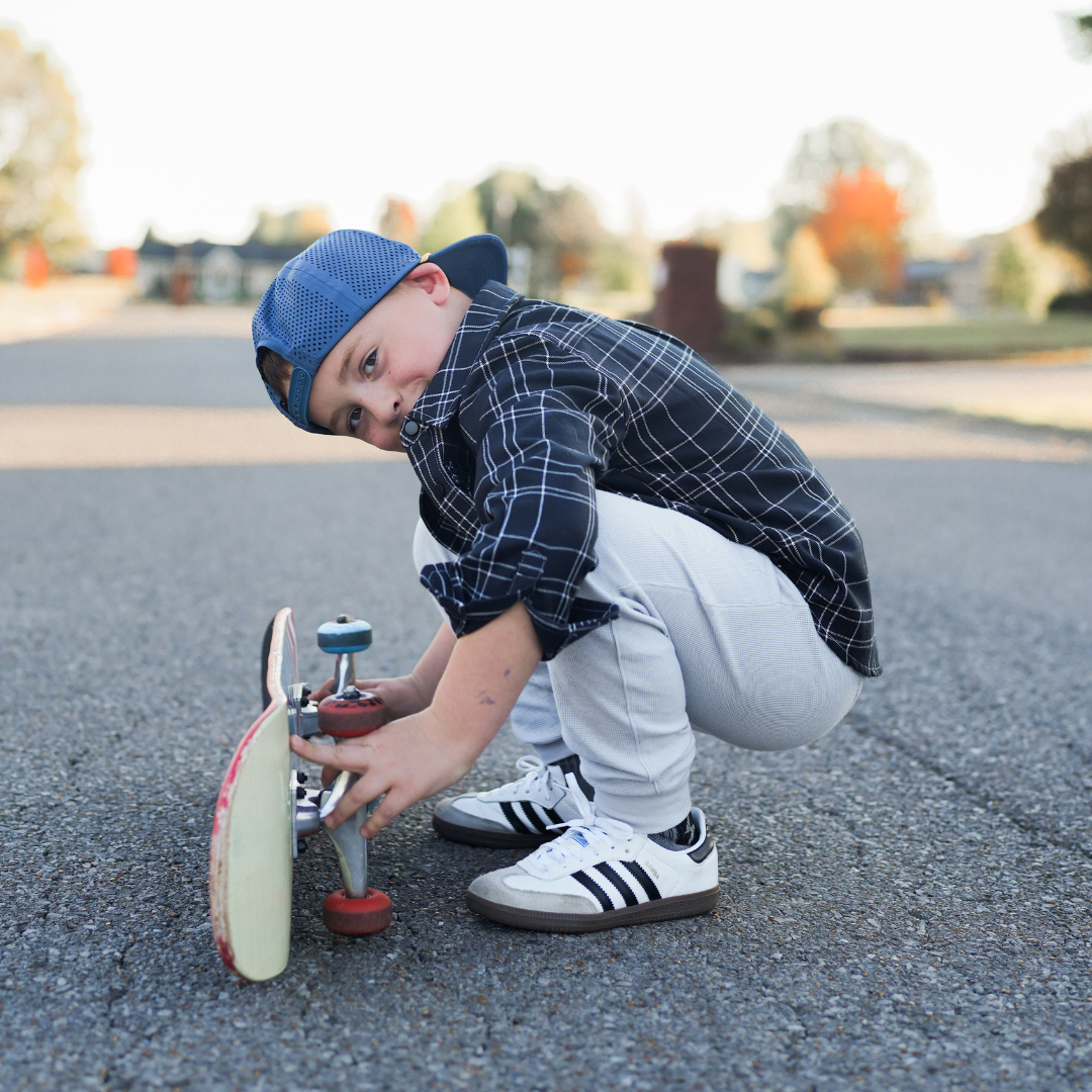 Boy with skateboard wearing blue Kids Flip Side Flannel and grey pants.