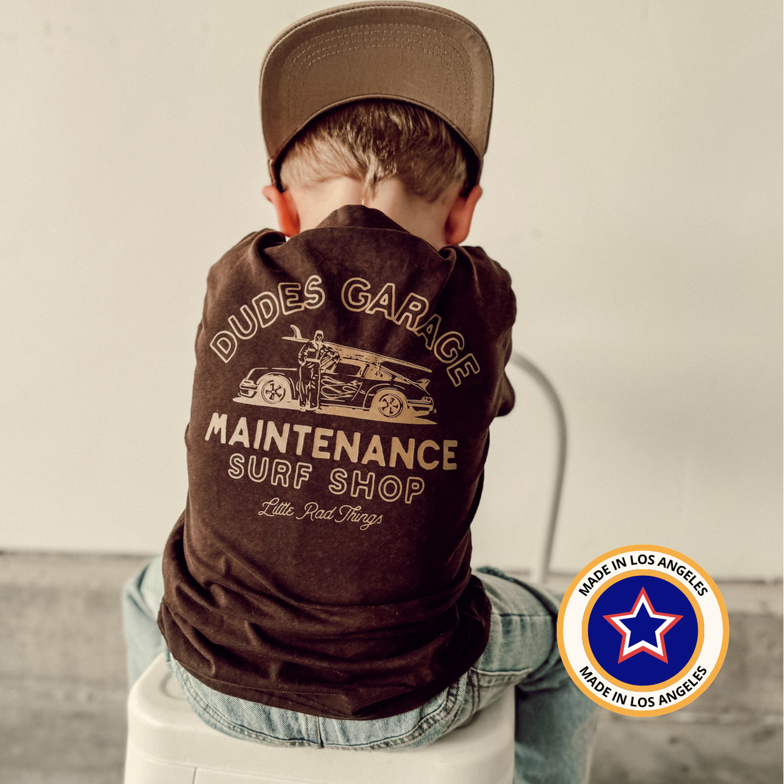 Boy wears Dudes Garage vintage brown tee with gold surf shop graphic.