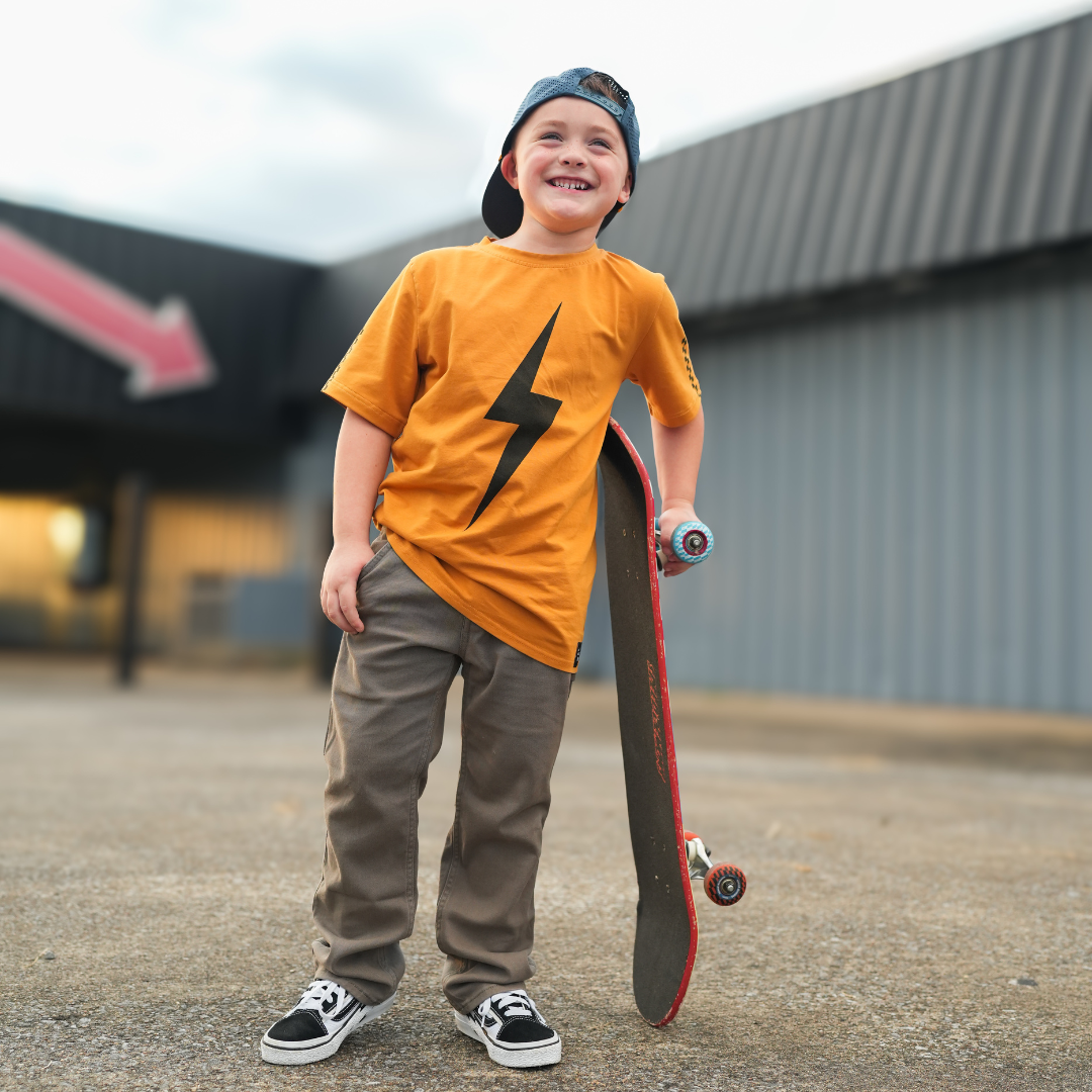 Boy in Pumpkin Spark Tee with Skateboard: A retro-inspired look for active kids.