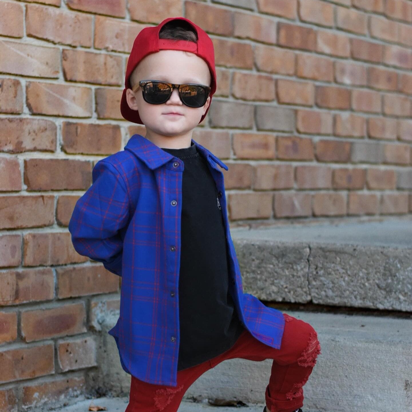 Boy in blue and red plaid Kids Fast and Free Flannel with jeans and red sneakers