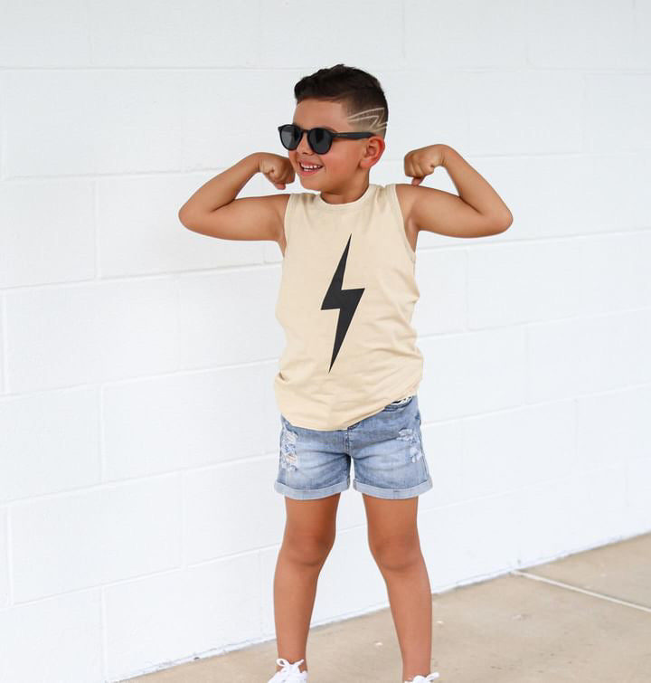 Toddler boy flexing in greige Spark Muscle-Tee with denim shorts