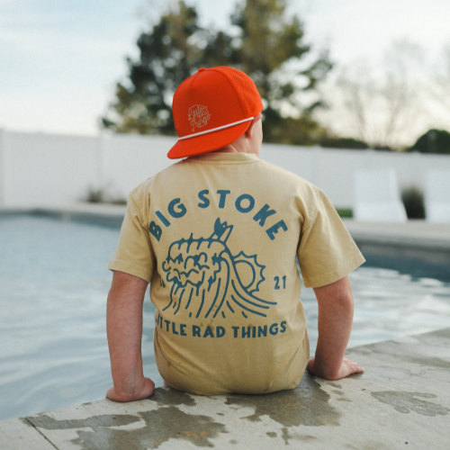 Boy in yellow beige Cloudbreak Tee with 'Big Stoke' graphic near pool.