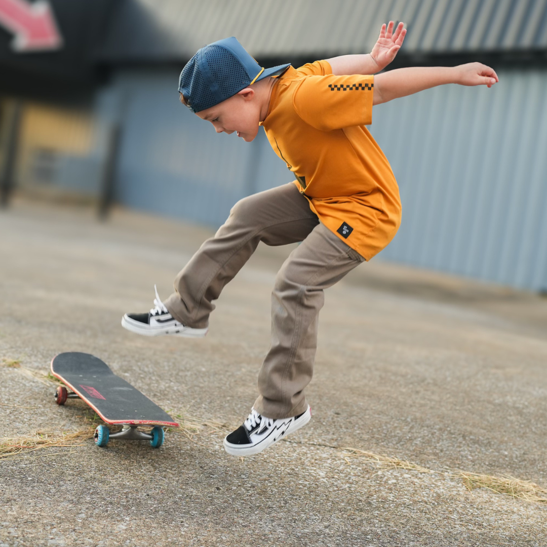 Boy in Pumpkin Spark Tee jumping off a skateboard: A cool, active look.