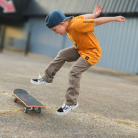 Boy in Pumpkin Spark Tee jumping off a skateboard: A cool, active look.