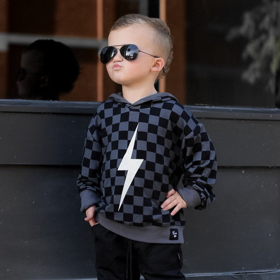 Child wearing black checkered Spark Hoodie smiling.