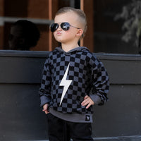 Child wearing black checkered Spark Hoodie smiling.