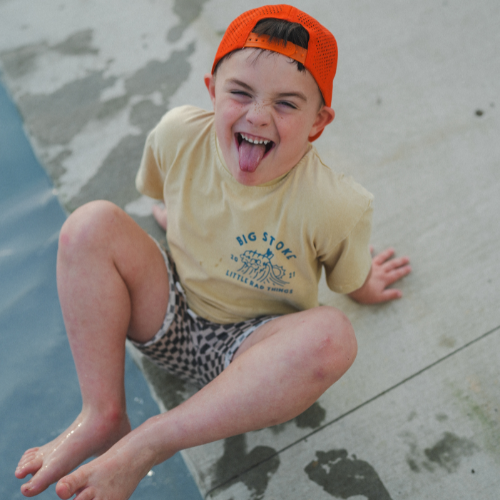 Playful boy in Cloudbreak Tee, making silly face near pool. 