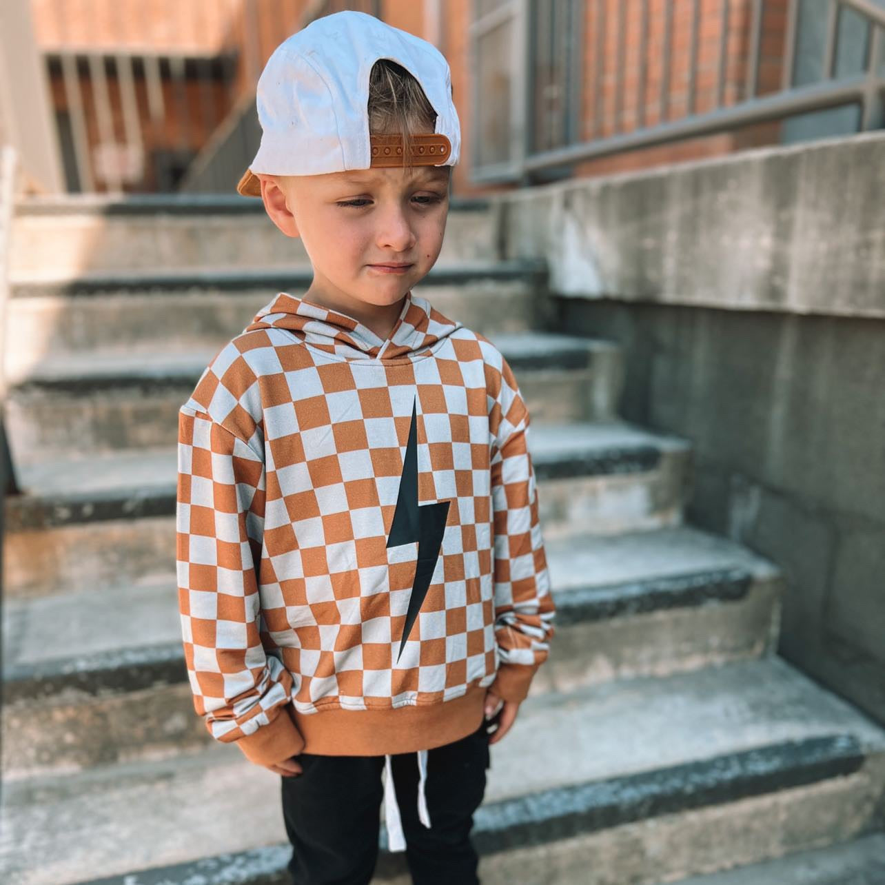 Close up of rust checkered spark hoodie on a hanger