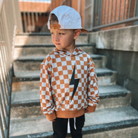 Child standing on stairs wearing a rust checkered spark hoodie.