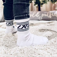 Toddler wearing white Classic Rock socks with LRT logo and jeans.