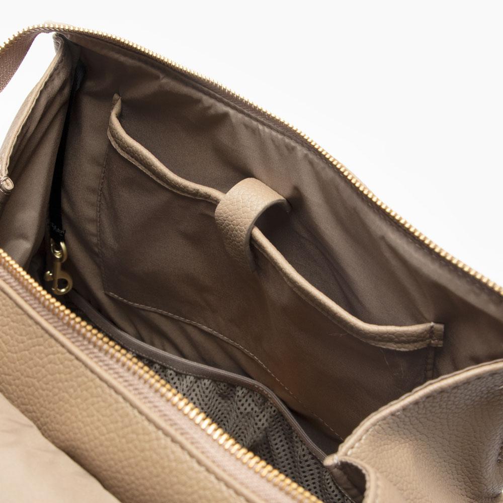 The Aspen Classic Diaper Bag II in stone next to a changing pad.