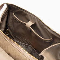 The Aspen Classic Diaper Bag II in stone next to a changing pad.