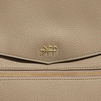 Close-up of the Aspen Diaper Bag II in stone, showing the logo and zipper detail.