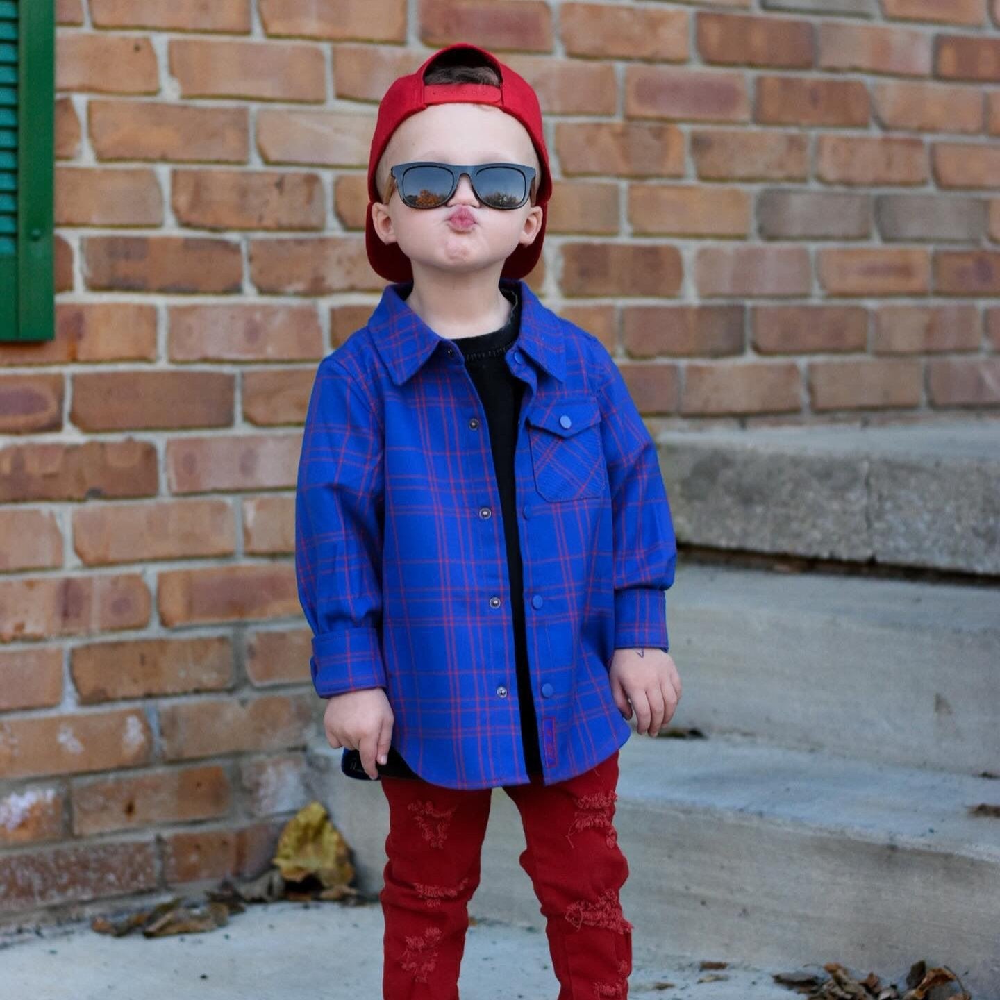 Boy in blue and red plaid Kids Fast and Free Flannel with jeans and red sneakers
