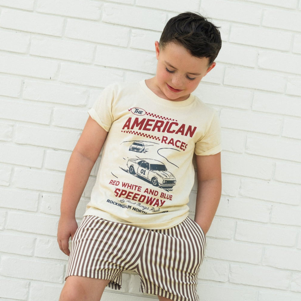 Boy wearing The All American Races cream tee with vintage race car graphic.