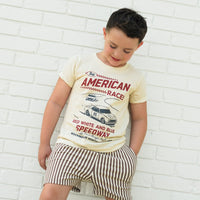 Boy wearing The All American Races cream tee with vintage race car graphic.