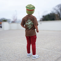 Boy wearing Cocoa Beach Tee, back view, outdoor setting.