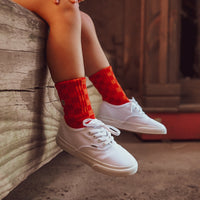 Child wearing Retrograde red/orange checkered socks with white sneakers.