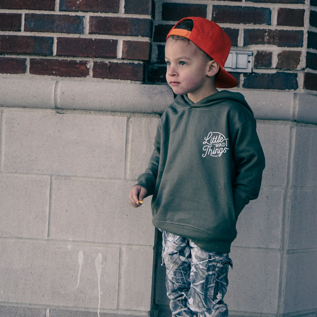 Boy wearing army green Radiator Hoodie with camo pants and orange hat.