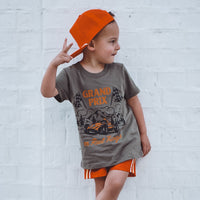 Child wearing military green Grand Prix t-shirt with peace sign.