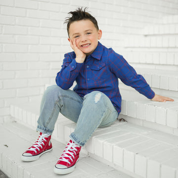 Boy in blue and red plaid Kids Fast and Free Flannel with jeans and red sneakers