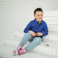 Smiling boy in blue plaid Kids Fast and Free Flannel on white steps