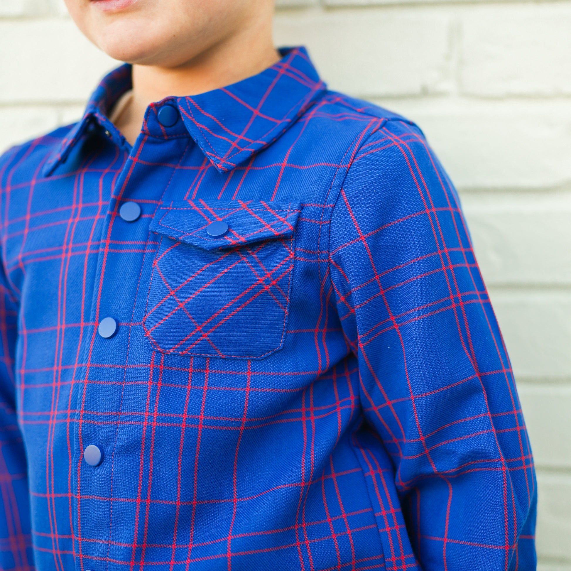 Close-up of blue and red plaid Kids Fast and Free Flannel with button pocket