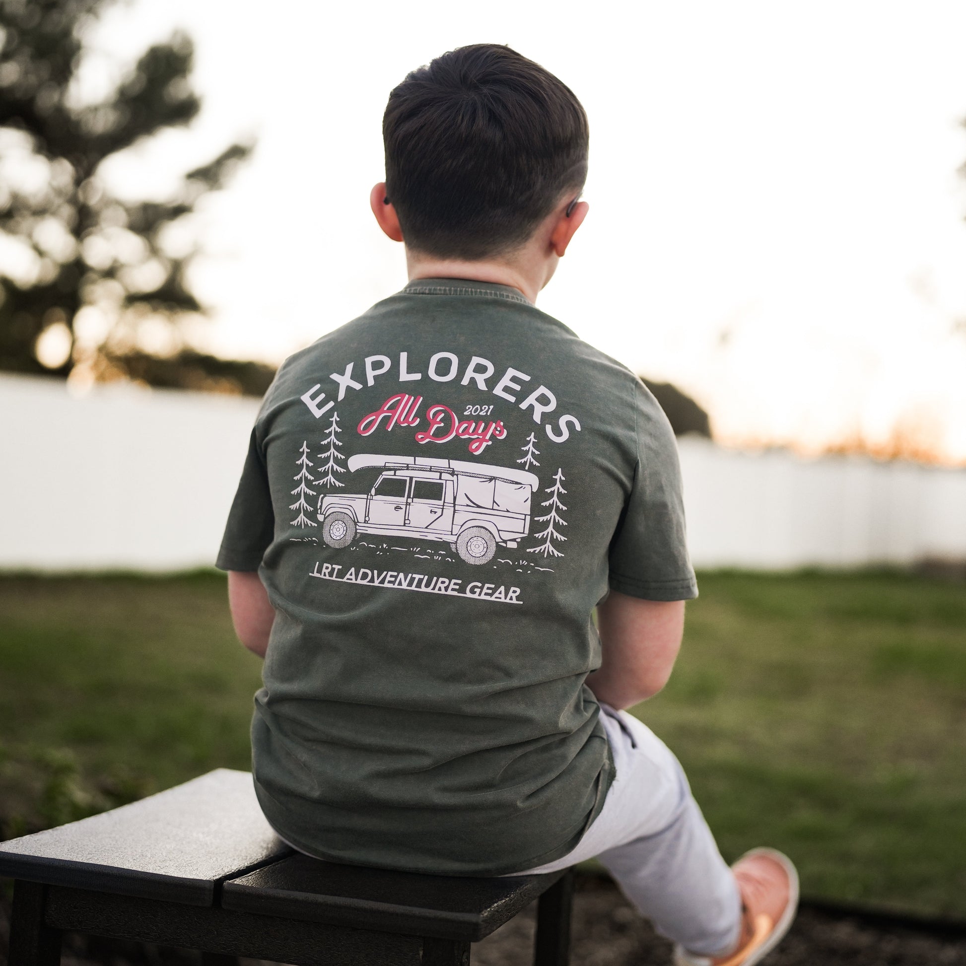 Child in sage green Explorer tee with adventure graphic.