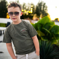Child in sage green Explorer tee with adventure graphic.