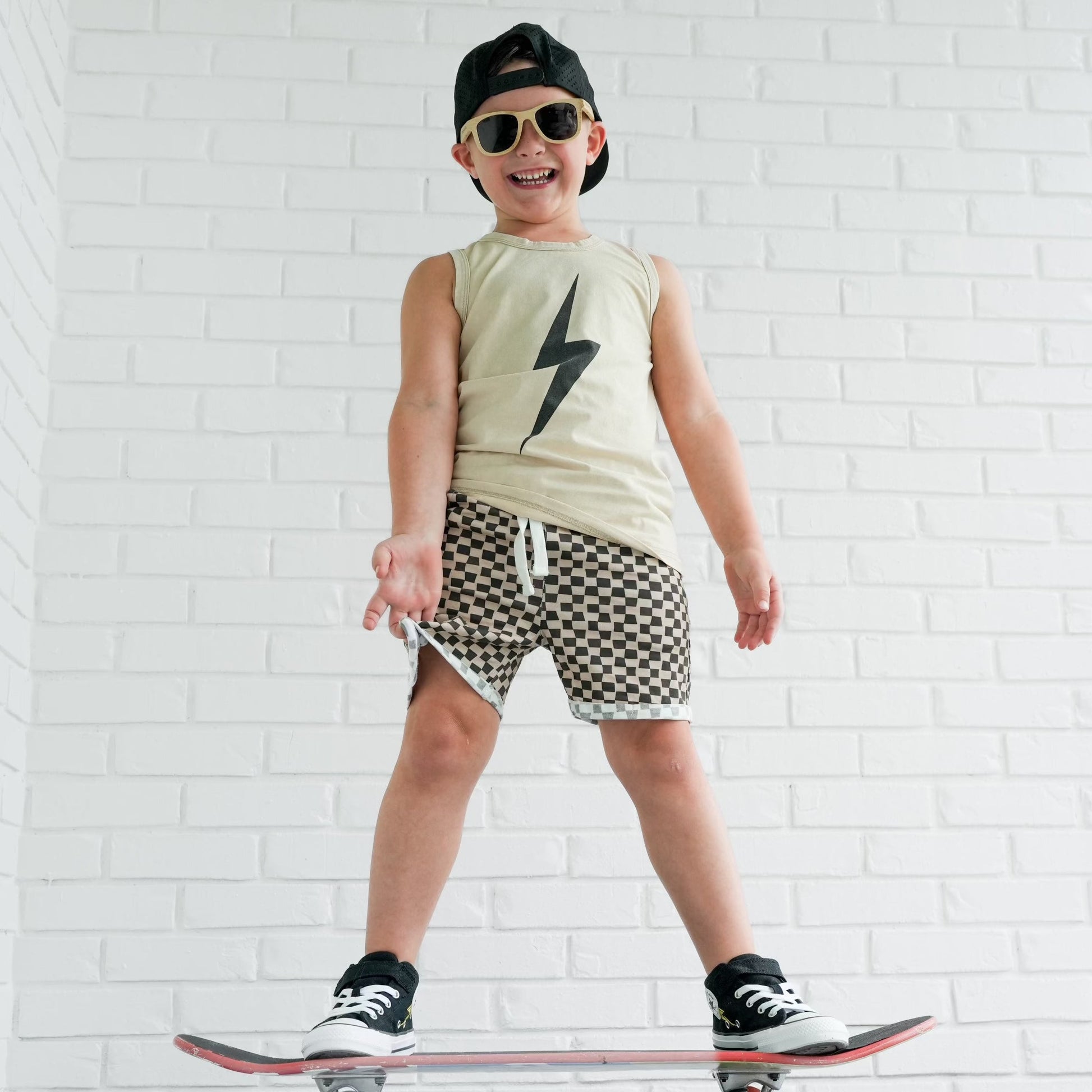 Toddler boy with lollipop wears greige Spark Muscle Tank