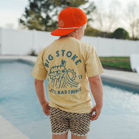 Back view of boy in Cloudbreak Tee and checkered shorts by the pool.
