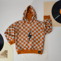 Rust checkered spark hoodie flat lay with vintage record decor.