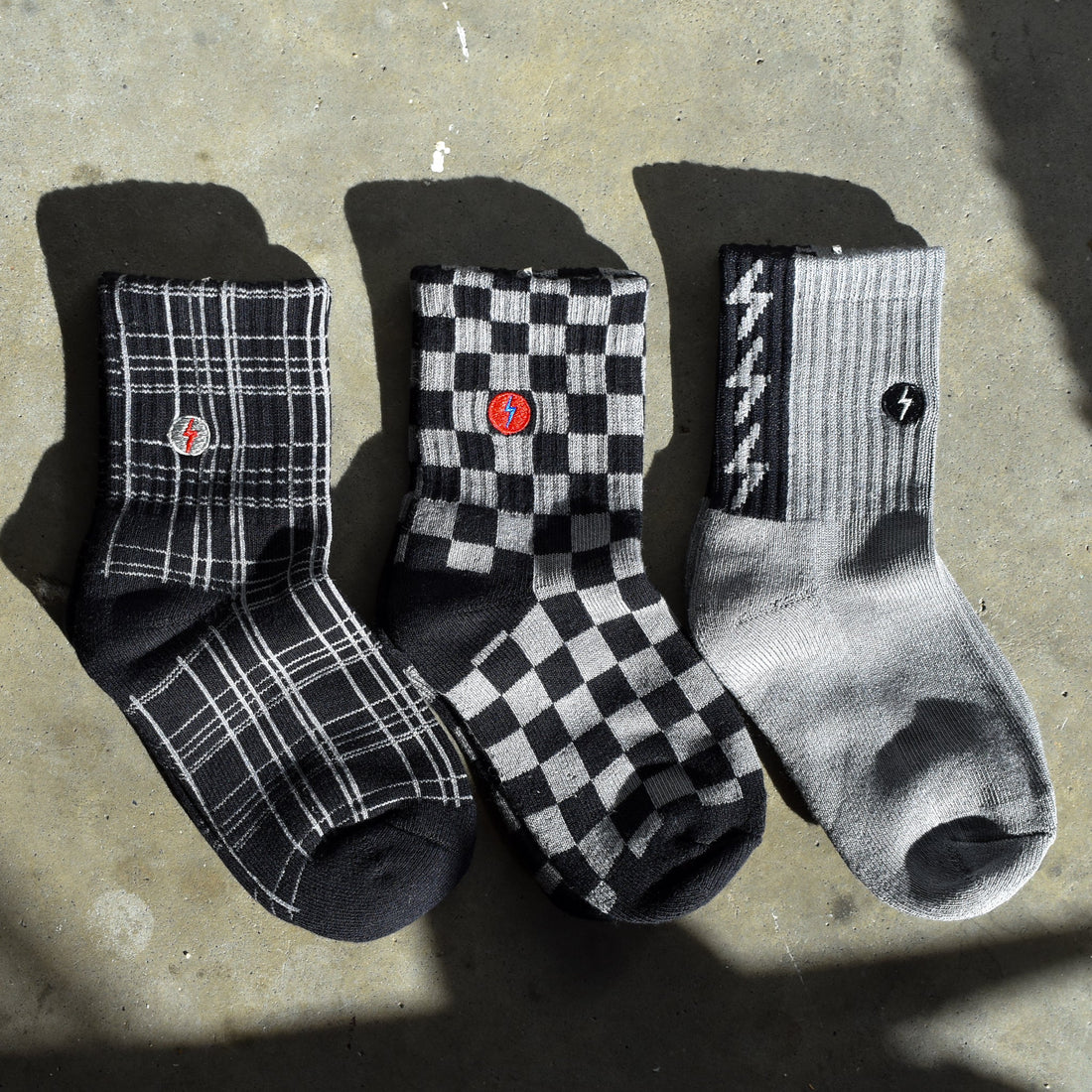 Checkered, plaid and lightning bolt socks displayed on concrete surface.
