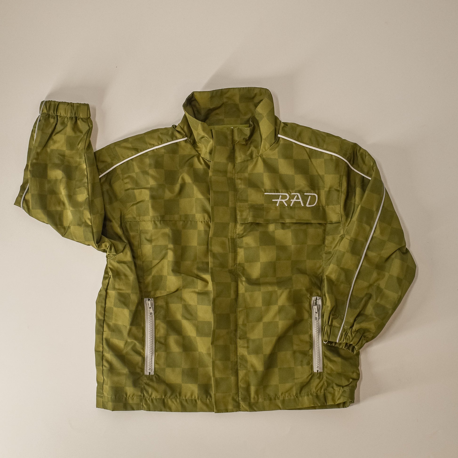 Storm Rider waterproof jacket in army green with checkerboard pattern, flat lay.