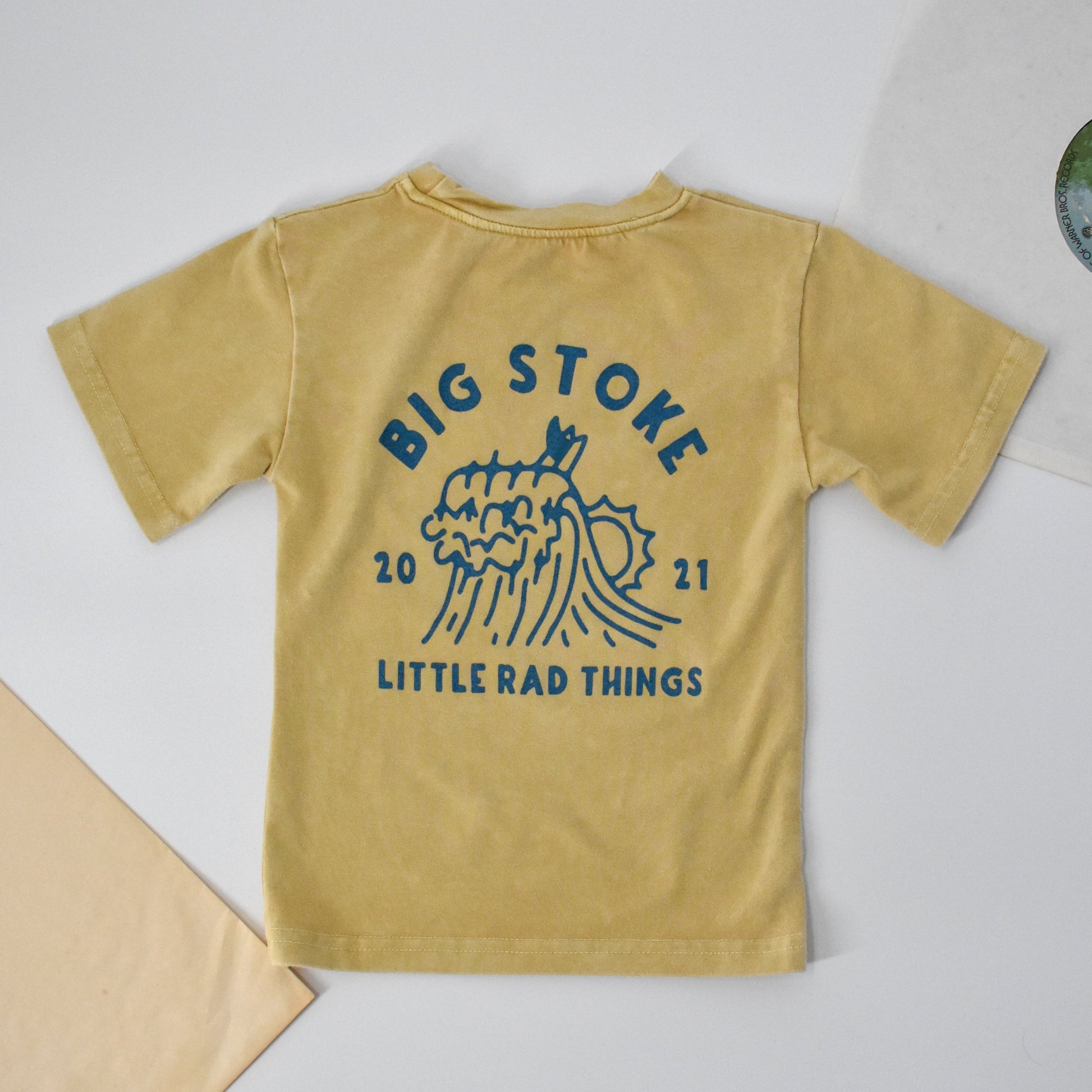 Close-up of yellow beige Cloudbreak Tee with 'Big Stoke' wave design. 